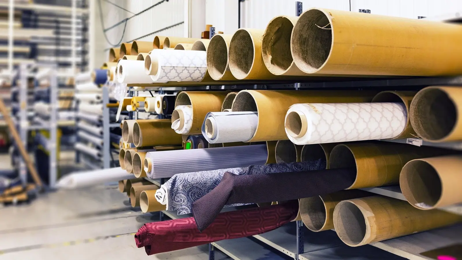 Textile fabric rolls stored on racks in a manufacturing workspace